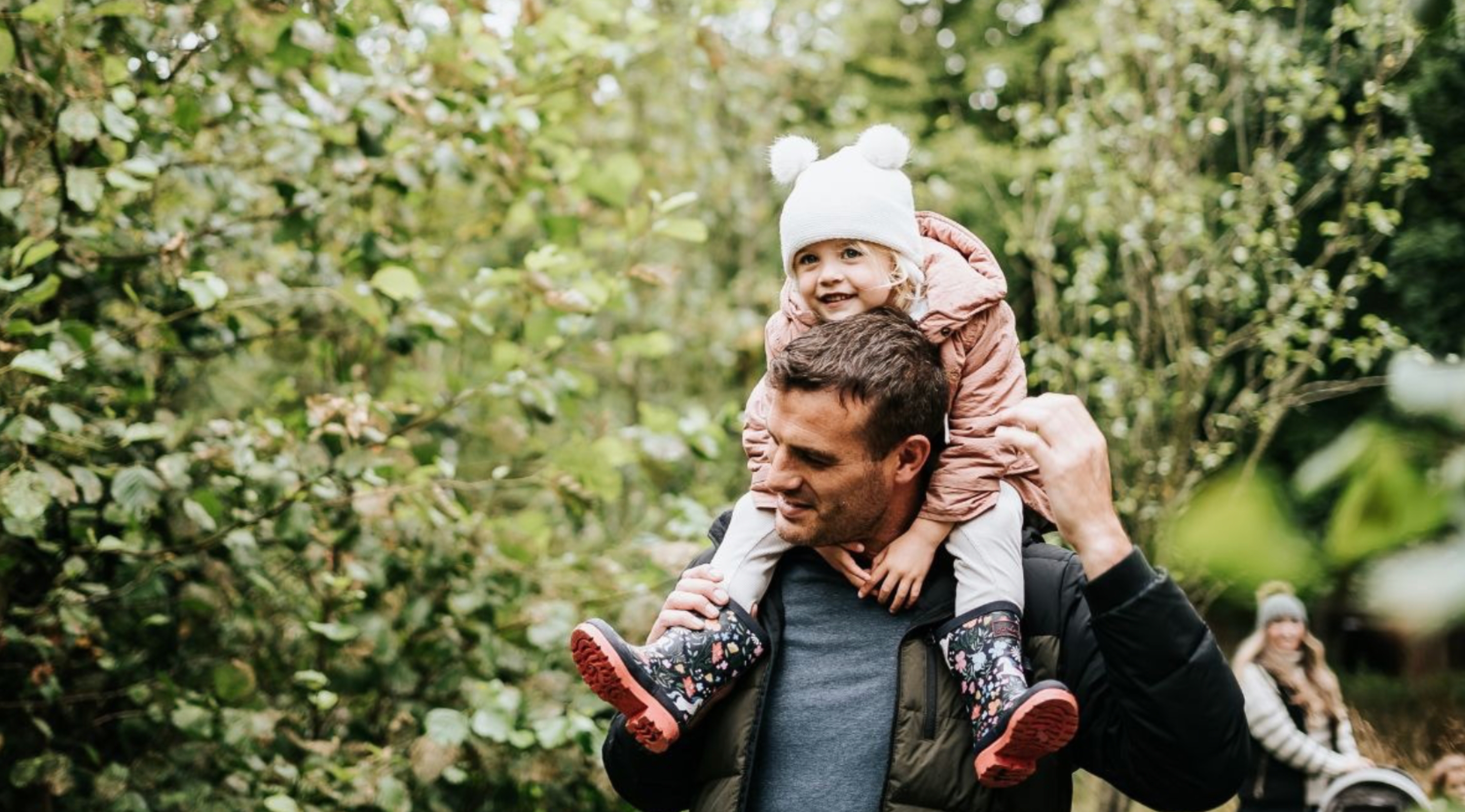 Father with his daughter on his shoulders walking woodland trails at Ribby Hall Village