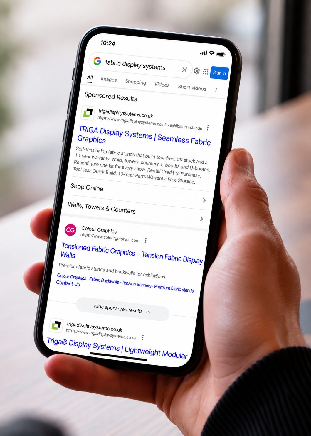 Phone showing a Google results page with sponsored ads above the organic listings