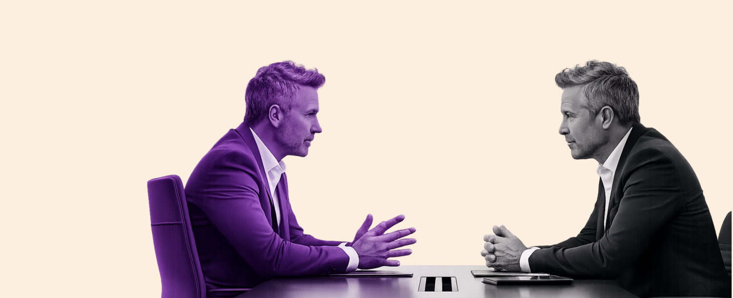 Two people in discussion across a boardroom table